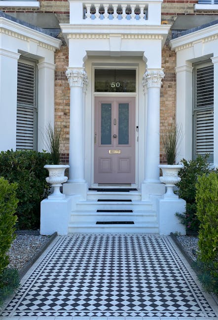 The image features a symmetrical front garden entrance with a central lavender-colored door set within a classic brick building. The door is framed by ornate white columns topped with decorative capit